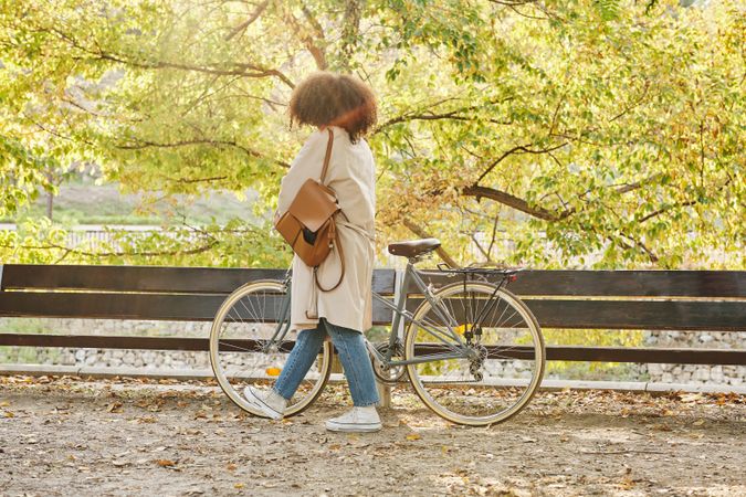 Woman in casual outfit with bicycle in park