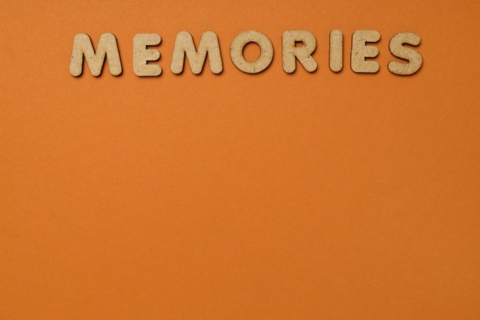 The word “Memories” written in cork on top of of dusty orange background, copy space