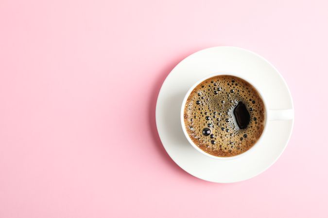 Cup of coffee on color background, space for text
