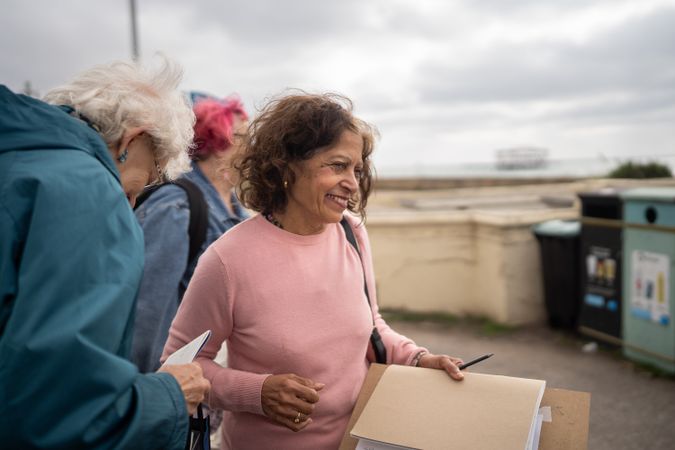 Smiling woman with friends walking with art supplies