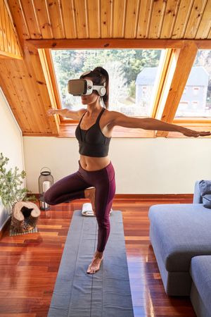 Female in headset balancing in Mountain pose with spread arms
