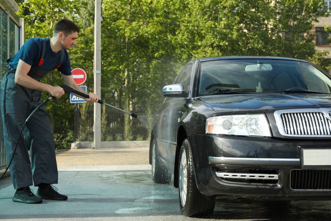 A man washes a car in a manual car wash. Clear car