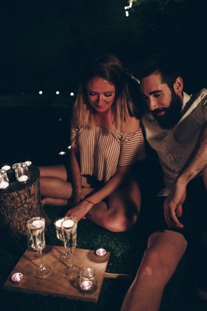 Couple with candles resting in night garden