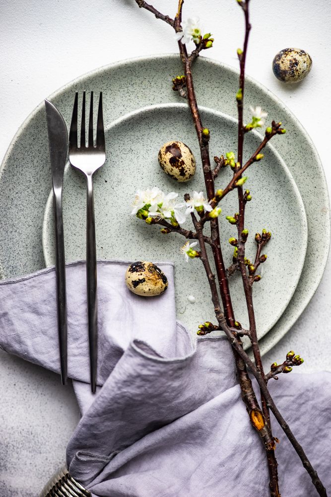 Festive table setting with speckled eggs on cherry blossom branch