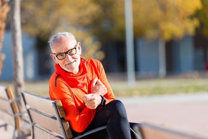 Happy older male sitting in park bench