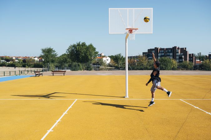 Young man playing on basketball court outdoor.