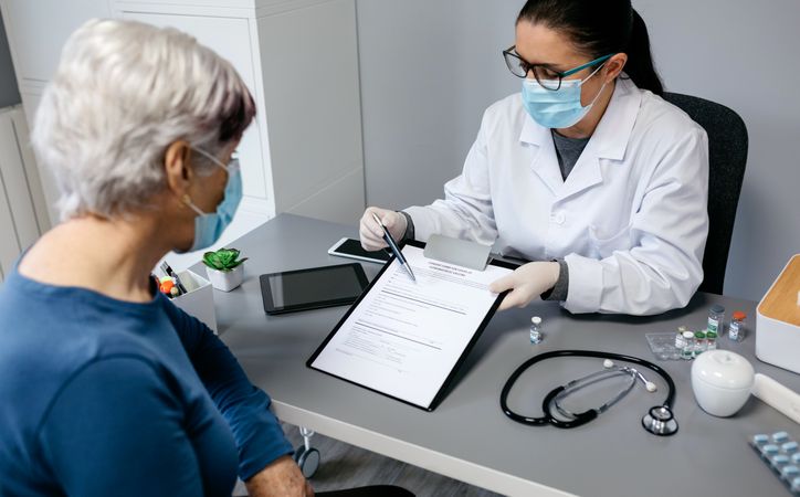 Doctor explaining to her patient consent form to coronavirus vaccine
