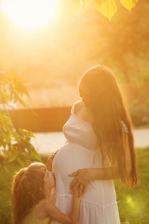 Daughter kissing her pregnant mother’s stomach