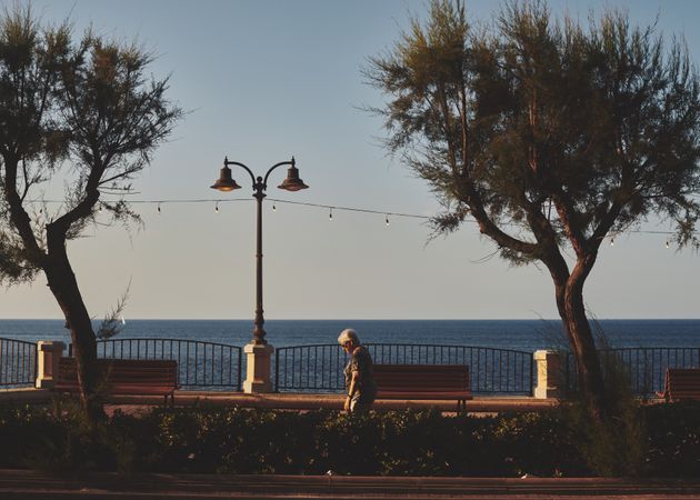 Side view of older woman walking along embankment in Malta