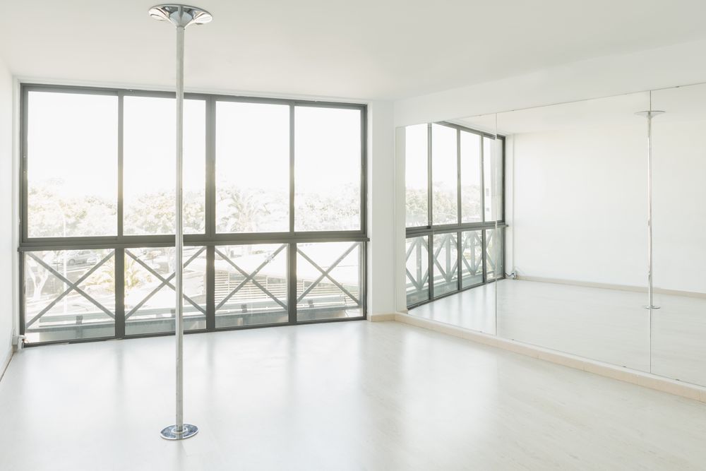 Pole dance studio with big mirrors and windows in light room