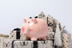 Piggy bank on gift boxes on light background, close up