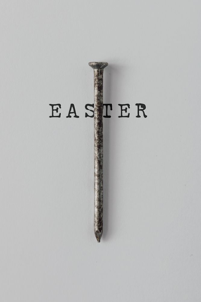 Nail on light background crossed with with word “Easter”