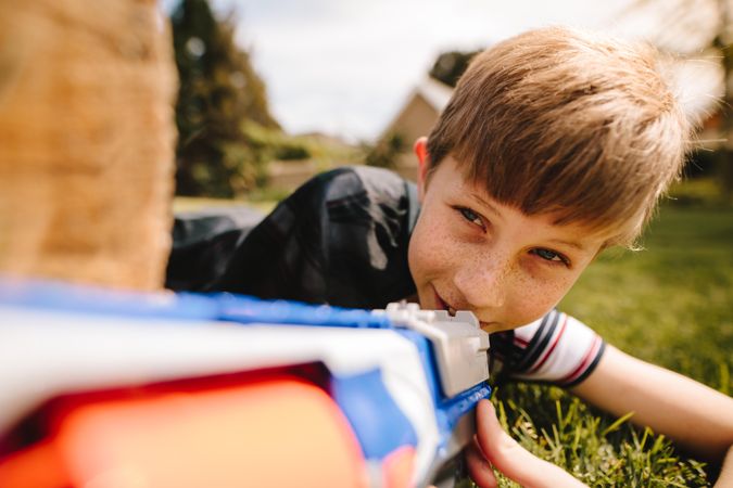 Boy with plastic toy gun in the grass