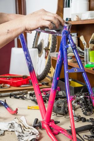 Hands of real bicycle mechanic sanding frame bike