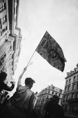 Monochrome shot of man carrying flag in Extinction Rebellion street protest in London