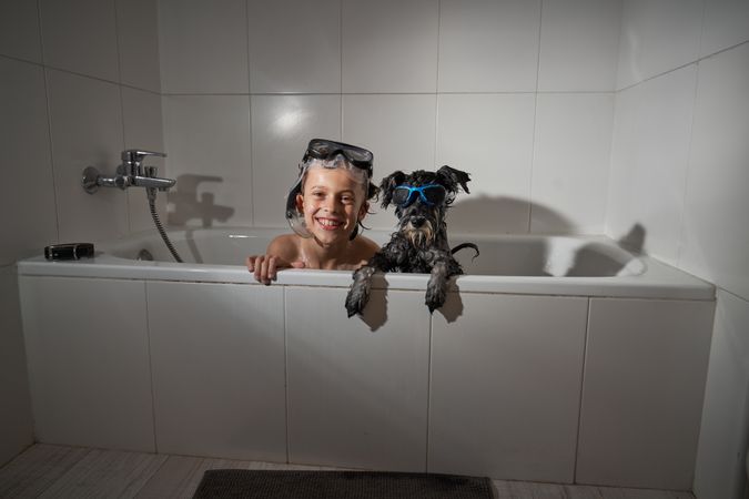 Delighted boy with dog in tub