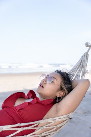 A young Hispanic woman sleeping peacefully on a hammock with an open mouth at the beach