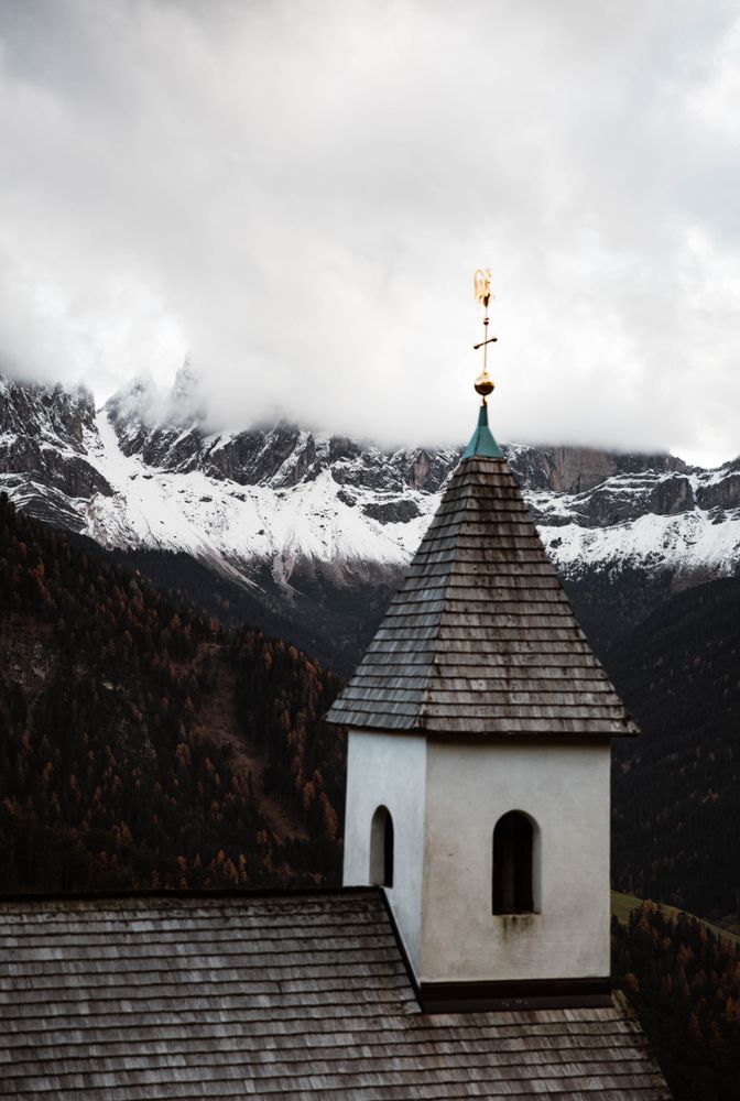 Small church on cliff near forest and mountains