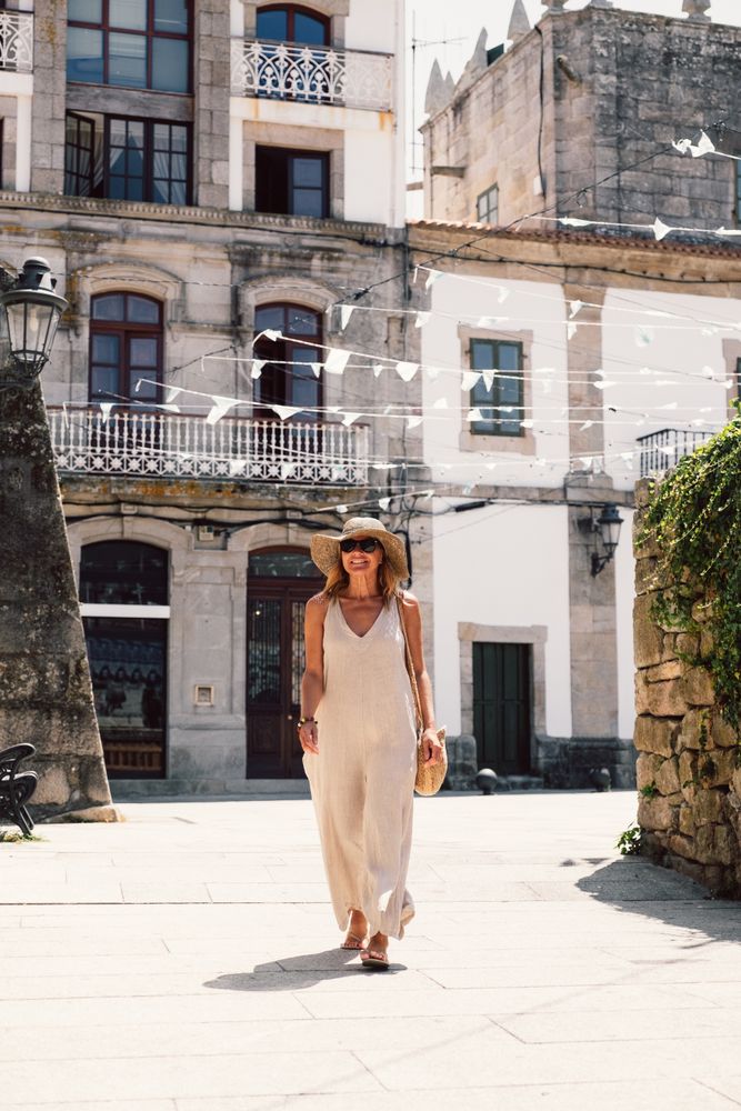 Woman in hat walking along sunny street