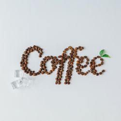 Coffee beans spelling out “Coffee” with ice cubes on bright background