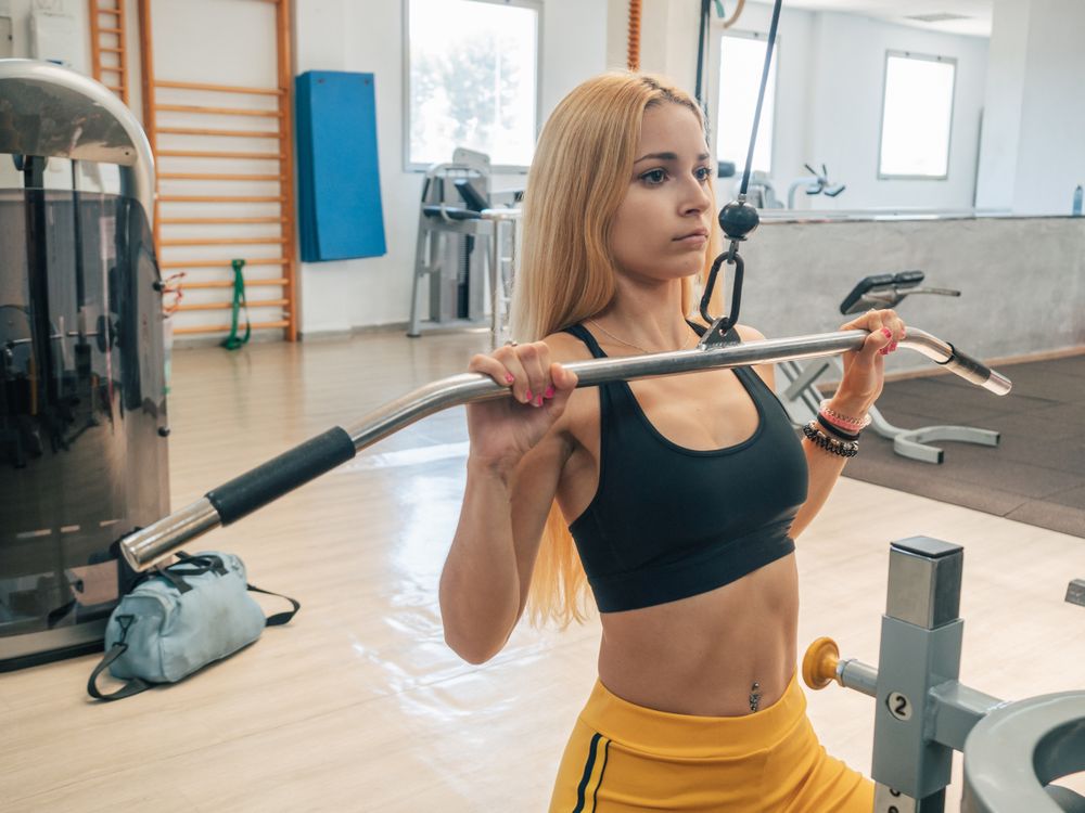 Fit woman doing lat pull-down exercise