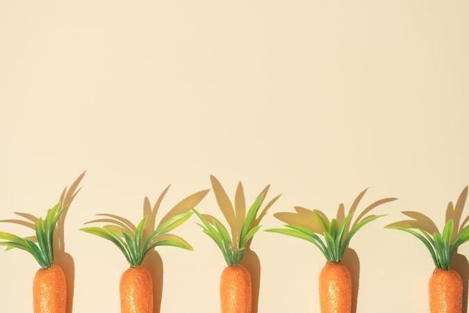 Row of carrots on pastel yellow background
