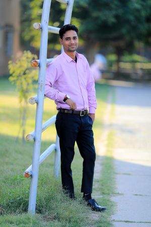 Man in pink dress shirt and dark pants standing outdoor