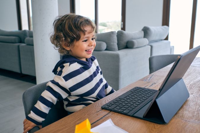 Cute boy watching cartoon on tablet in living room