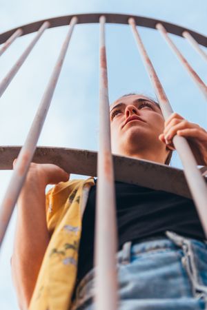 Thoughtful female leaning on metal fence