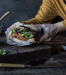Hands with sandwich with vegetables and pate on tray