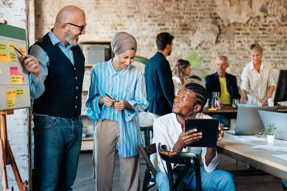 Multi-ethnic office with colleagues gathering around the board with ideas