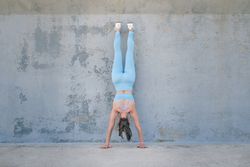 Anonymous athlete standing on hands against rough wall
