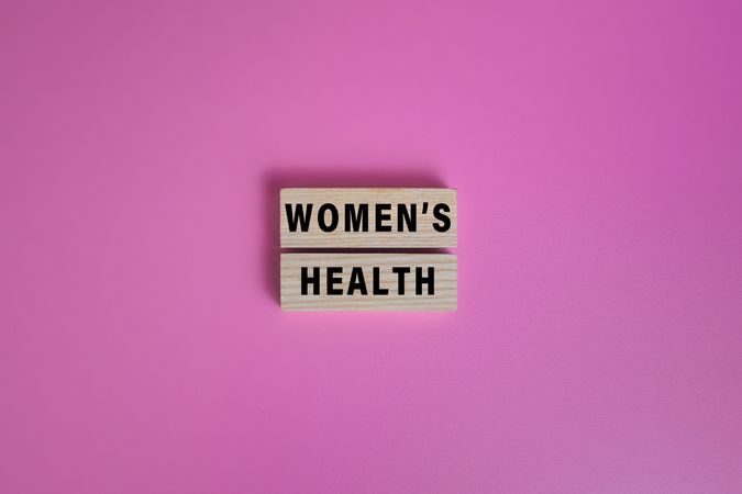 women health words text on wooden blocks isolated on pink background
