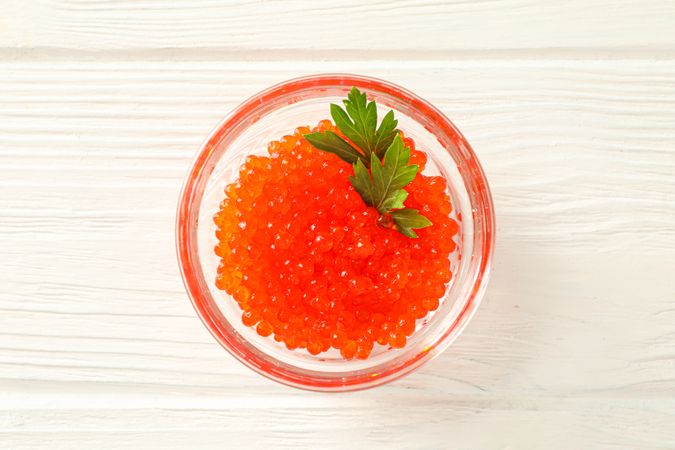 Glass jar with red caviar isolated on wooden table, space for text