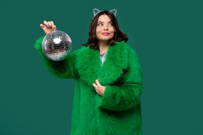 Playful woman in green fur coat looking aside