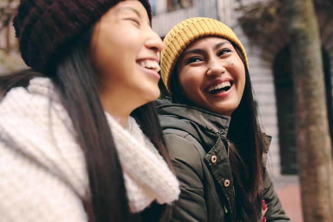 Two happy young Asian women laughing together