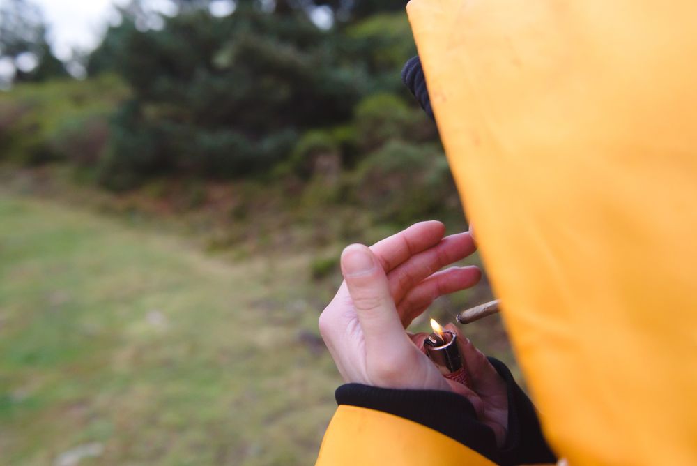 Person in yellow raincoat lightening cigarette