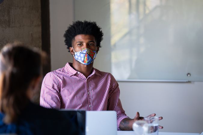 Man in brightly colored face mask talking with colleague