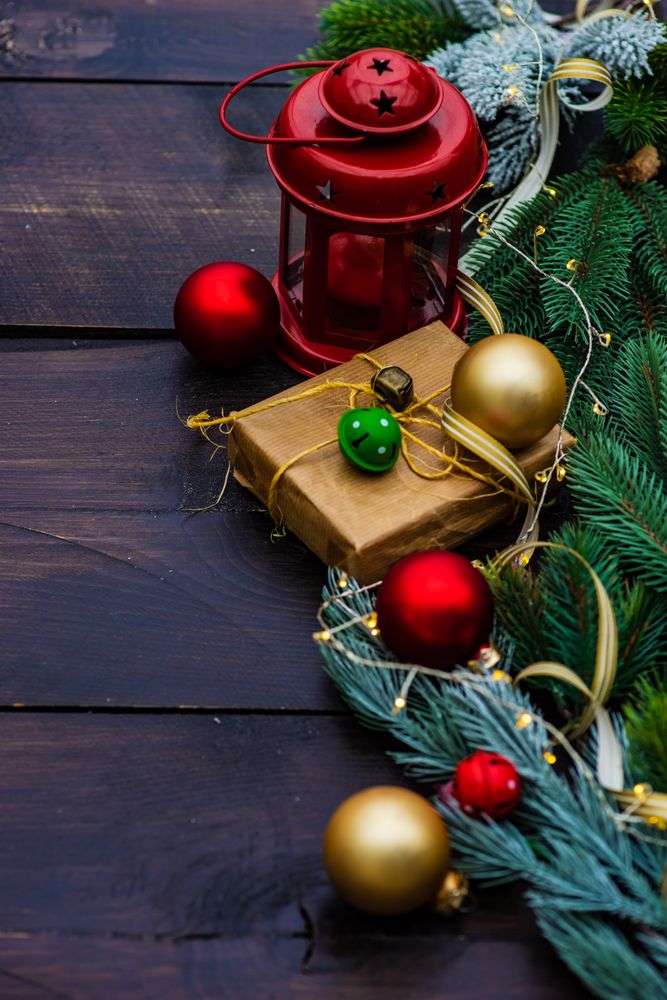 Christmas gift wrapped in brown paper surrounded by baubles with light string
