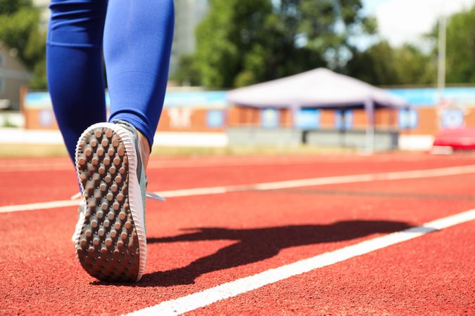 Girl walking on red athletic track, space for text