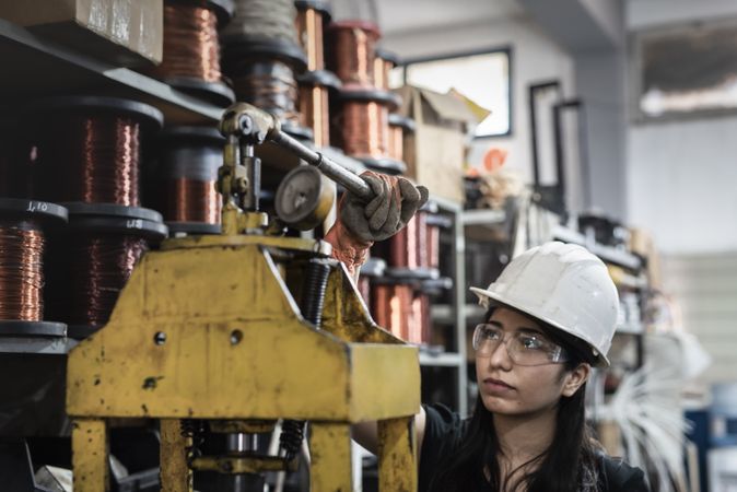 Woman in hard hat holding brown metal pipe