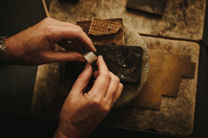 Close up of a female jeweler hands working on a ring at her workbench