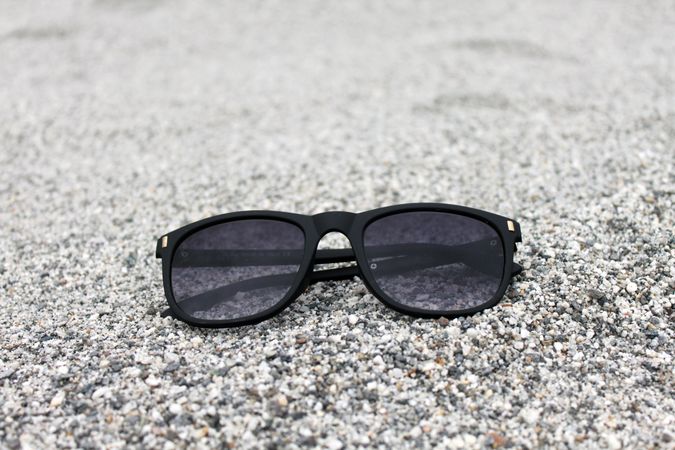 Sunglasses on grey sand