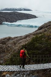 Person with backpack walking on rope bridge