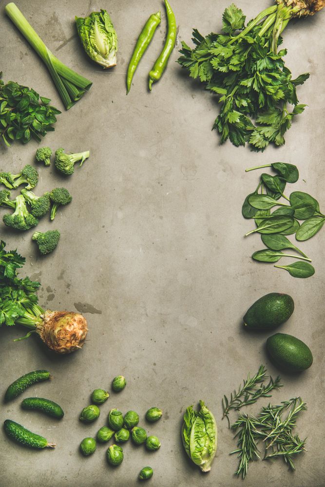 Arrangement of fresh green garden vegetables on concrete surface, copy space, vertical composition