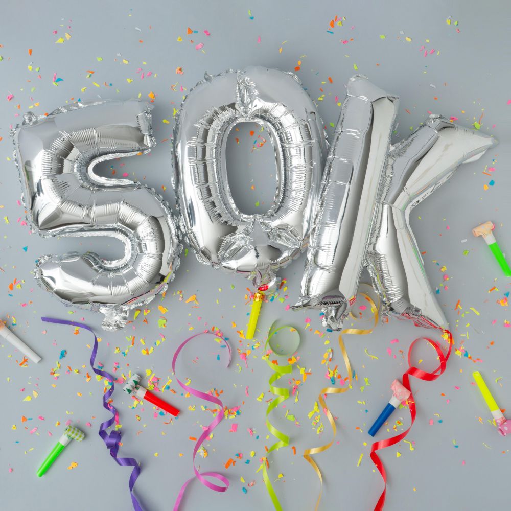 Silver balloons reading 50k with confetti