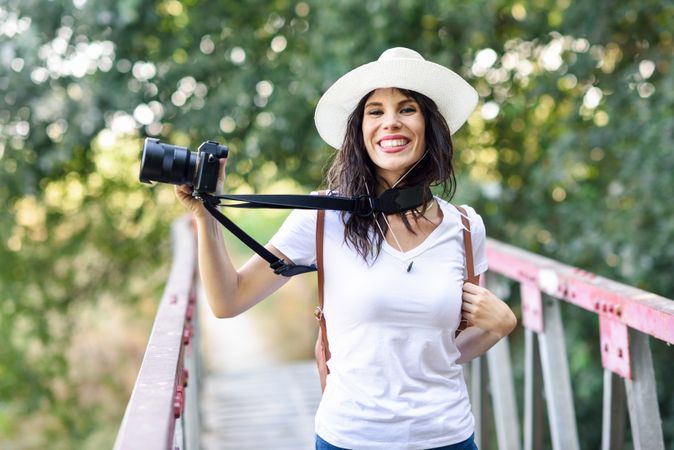 Happy woman walking with SLR camera, wearing straw hat outside