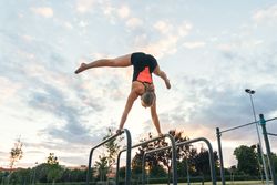 female athlete doing handstand on parallel bars