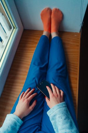 Crop woman in home clothes on window sill