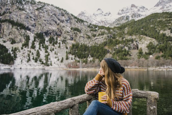 Woman on seat near wonderful lake between hills in snow